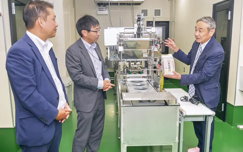 あっとんの神原轟社長(右)から工場設備などの説明を受ける久次米辰倫エリア長(左)と白崎誠之支店長代理(8月19日、高松市内)