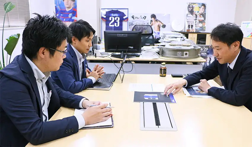 半導体製造装置部品の製造、加工を担うサワの山口代表取締役(右)と情報を交換する行員ら(上野原市)
