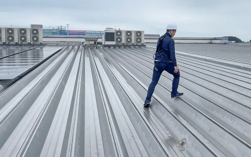 太陽光パネルを設置した屋根の周辺を点検する作業員(カワチ薬品上三川インター店、クリーンエナジー・ソリューションズ提供)