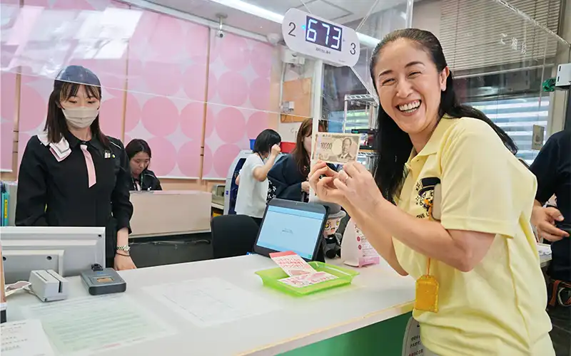 城北信用金庫が新1万円札発行を記念して開いたイベントで、新札を両替する東京都北区の山田加奈子区長＜右、7月3日＞