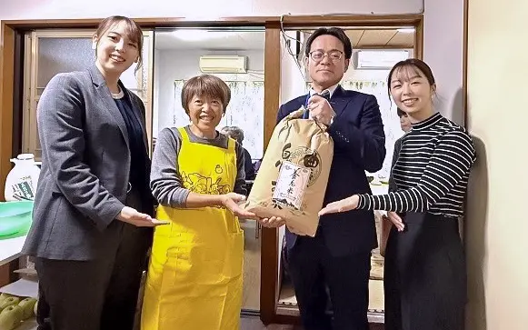 高橋由美子・みんなの食堂ママごはん運営代表者(左から2人目)に収穫した米を贈呈した吉田健一・福生兼牛浜支店長(右から2人目)、同支店の担当者たち(西武信用金庫提供)