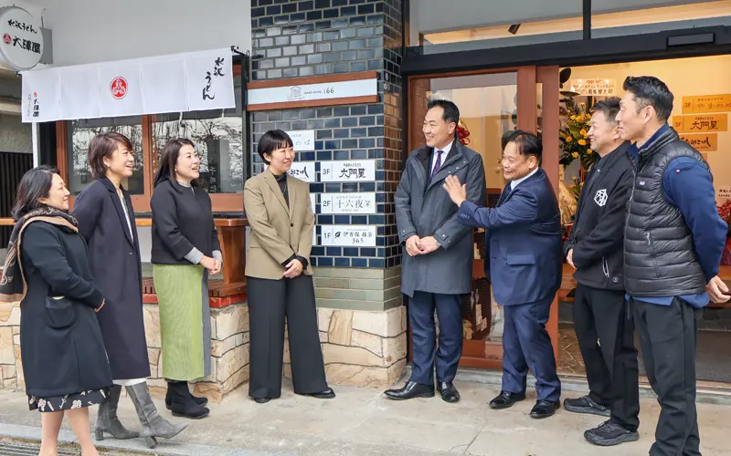 IKAHO HOUSE166の前でファンド出資事業者らと交流する清水郷平支店長（左から５人目、2024年12月20日）