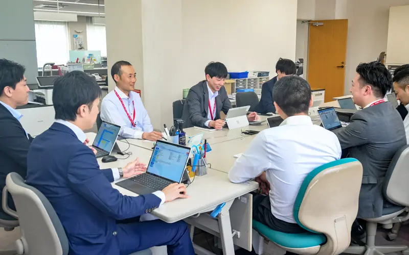 フリーアドレスの業務室でミーティングをする佐々木義幸支店長(左から3人目、5月2日、秋田銀行横手支店)