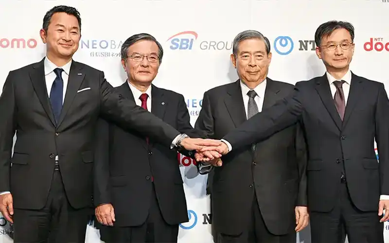 会見後、手を合わせる（左から）NTTドコモの前田義晃社長、日本電信電話の島田明社長、SBIホールディングスの北尾吉孝会長兼社長、住信SBIネット銀行の円山法昭社長（5月29日、ホテルニューオータニ東京）