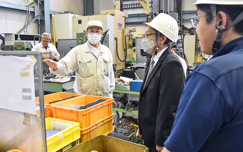 精密加工業のナノ社の社員(左から2人目)から説明を受ける職員ら(6月13日、横浜市内)