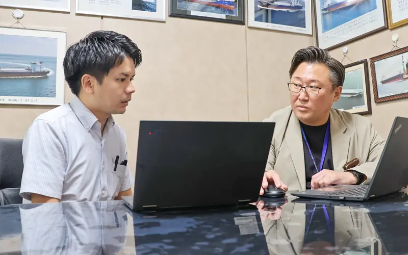 取引先の船の写真が飾られた部屋で話し合う満尾優一支店長（右）と松村崇史課長代理（９月３日、熊本銀行大矢野支店・松島支店）