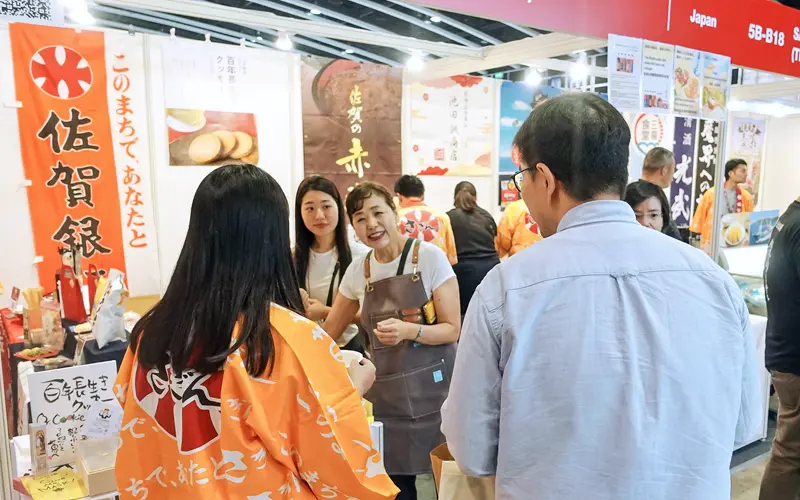 佐賀銀行は、８月に香港で開催されたアジア最大級の食品見本市に取引先と出展。海外短期研修の一環で、派遣行員もサポート（８月14日、香港コンベンション＆エキシビション・センター、佐賀銀行提供）