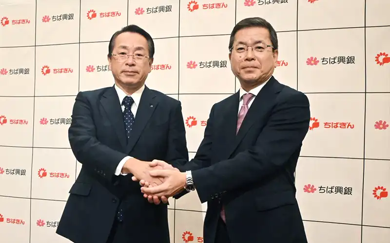 会見後握手する米本努頭取(左)と梅田仁司頭取(9月29日、千葉市内のホテル)
