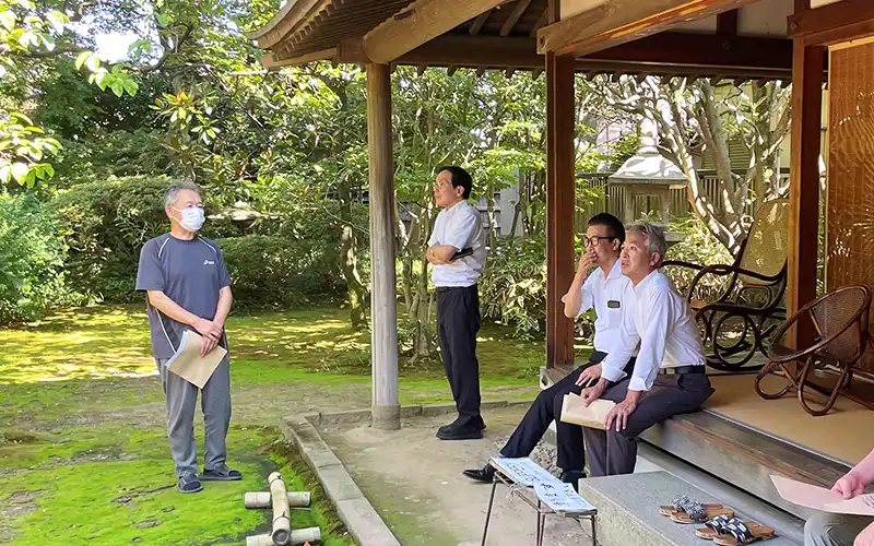 旧風間家住宅丙申堂で説明を聞く（左から）田尾祐一・荘内銀取締役、エイチ・アイ・エスの山野辺淳取締役ら（8月18日、鶴岡市、荘内銀提供）