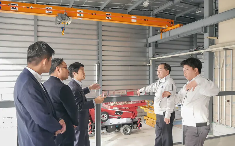 井上俊裕社長（左から４人目）と井上永策専務（同５人目）から新工場の特徴を聞く（左から）稼勢秀樹副支店長、赤岩志洋支店長代理、小山田貴志支店長（11月４日、四国車体）