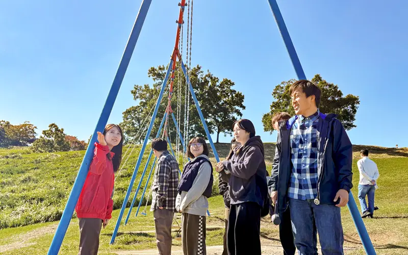 学生に伐株山の山頂の地形を教える富永有香さん（左、10月29日、玖珠町）