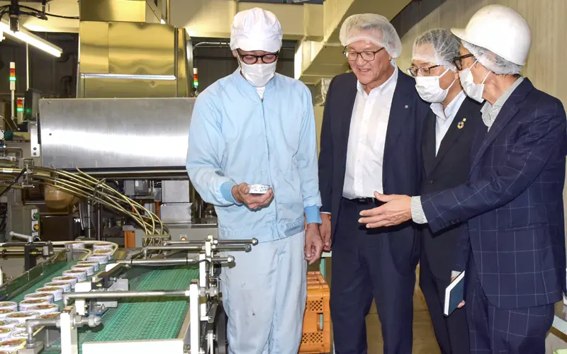 缶詰工場でサスナの土田幸一郎社長（右）から説明を受ける高田淳代表取締役（左から２人目）ら（10月28日）