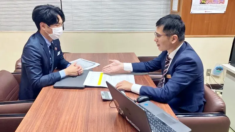 顧客との面談前に支店行員（左）にPSSを説明するエキスパート（２月６日、北中城支店、琉球銀行提供）