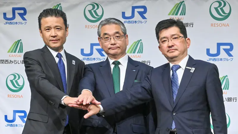 手を合わせる(左から)南昌宏・りそなHD社長、倉坂昇治・JR西日本社長、原藤省吾・関西みらい銀行社長(5月1日、大阪ステーションホテル)