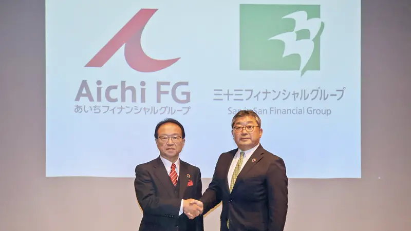 握手する伊藤行記・あいちFG社長(左)と道廣剛太郎・三十三FG社長(5月13日、名古屋市内)