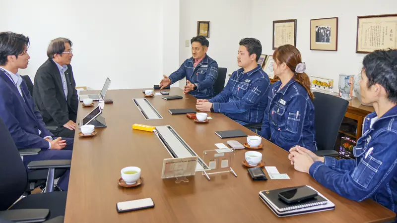イナミコーポレーションの稲見政隆社長（左から３人目）らに新事業の進ちょくなどをヒアリングする、愛媛銀行西条支店の（左から）西村祐哉主任と高橋彰支店長（５月１日、イナミコーポレーション）