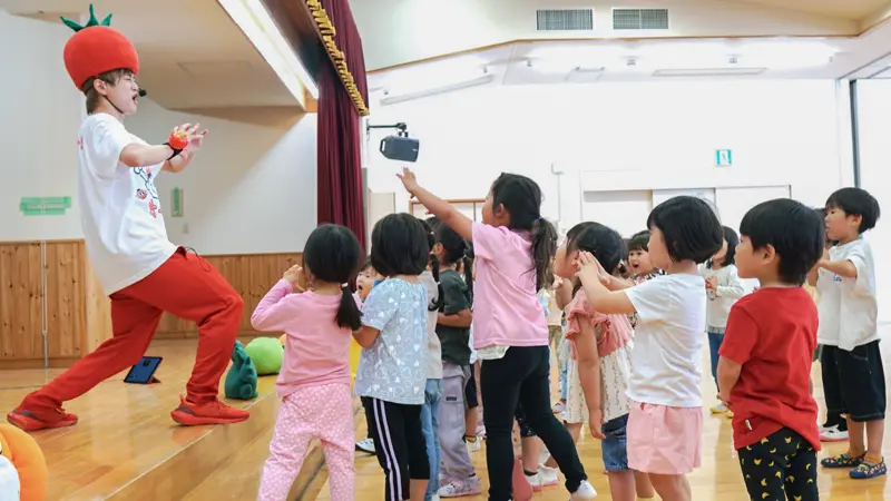 トマト兄さんちゃす(左)の歌と踊りを楽しむ園児ら(5月14日、三島市立錦田保育園)