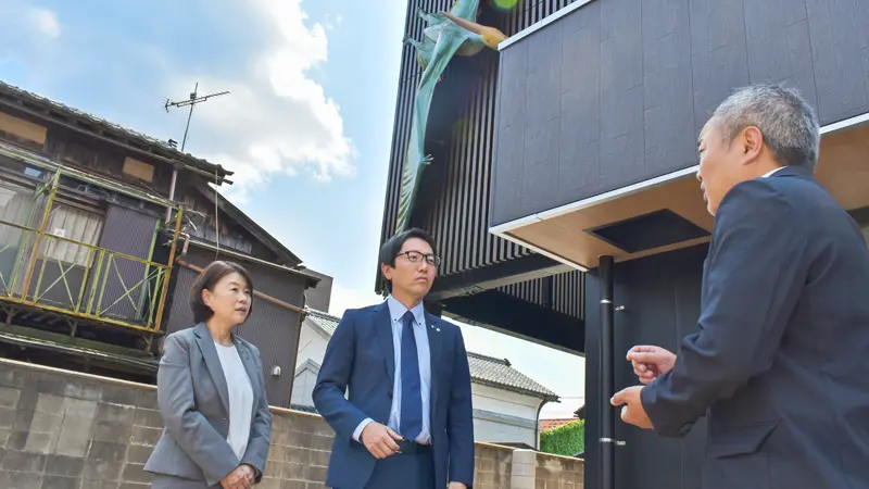 プテラノドンのオブジェがある北陸銀行勝山支店前で談笑する(左から)の玉木祐子勝山支店長、中野知育エリア統括、大北久保建設の和田晃幸社長(6月11日)